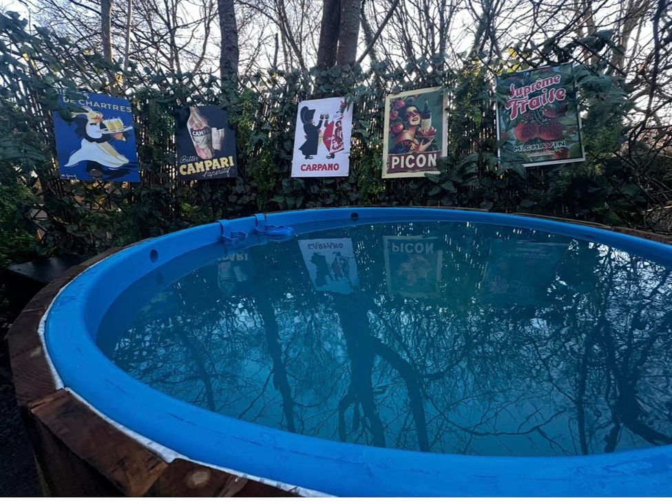 A hot tub with posters on a fence in an outdoor area at The Old Barn in Bovey Tracey
