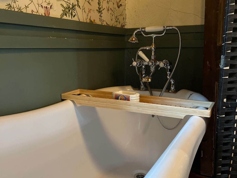 A bathtub with a wooden shelf and faucet in a bathroom at 
