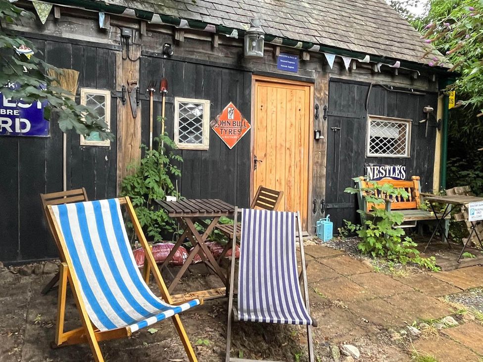 An outdoor area with deck chairs and wooden furniture at the property in Bovey Tracey