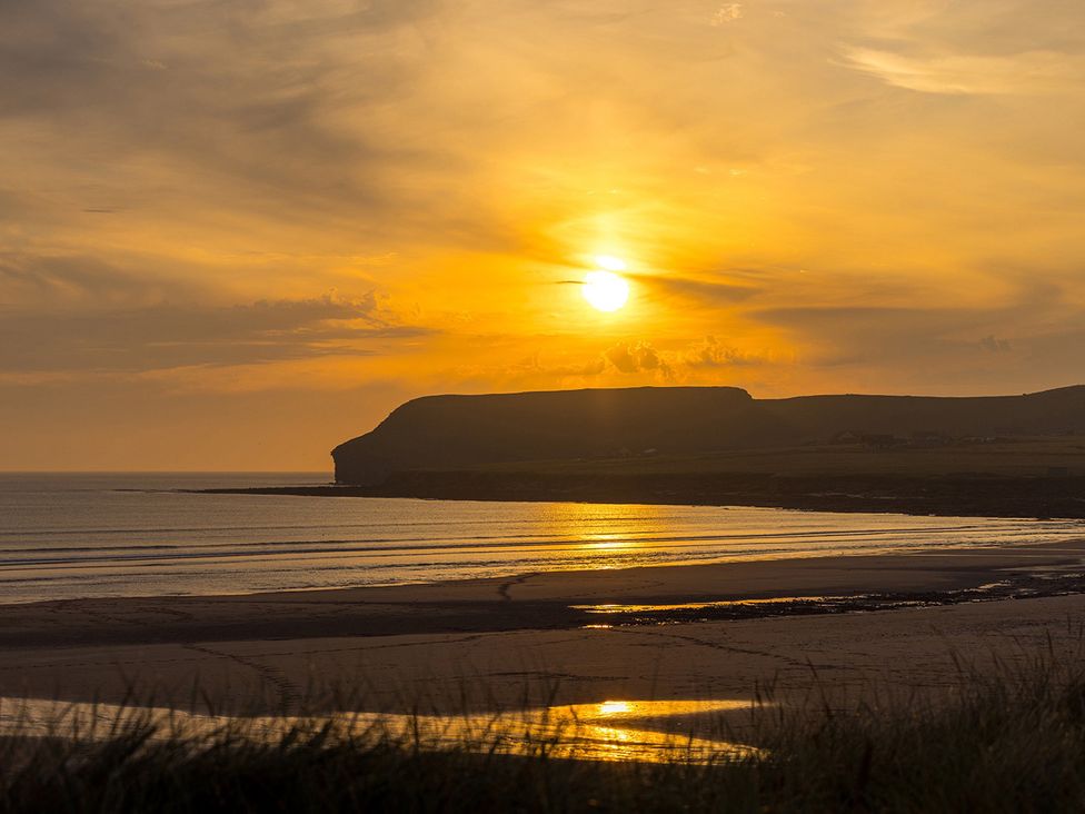 A sunset over the sea with hills in the background at Short Walk to the Beach - 2 Guests - Free Parking in Thurso