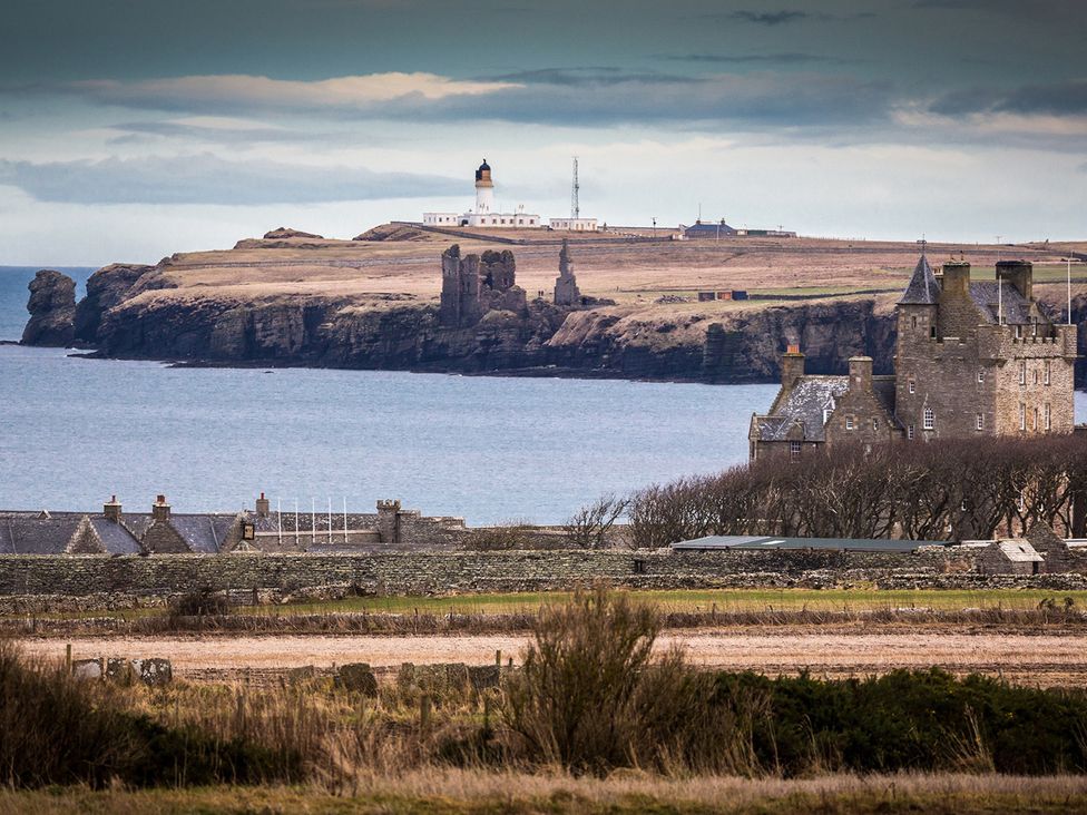 A view of a lighthouse and ruins near the ocean at Short Walk to the Beach - 2 Guests - Free Parking Thurso