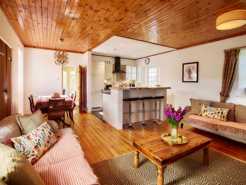 A living room with a sofa, table, and kitchen area at a property near Edinburgh