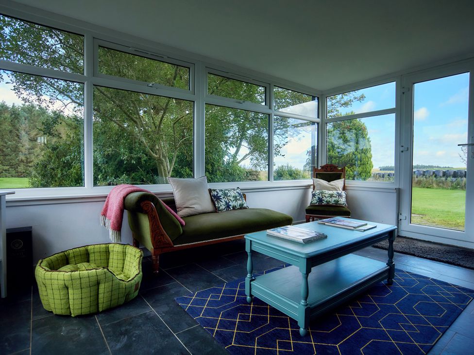 A conservatory with a sofa and coffee table at The Old Barn in Near Edinburgh