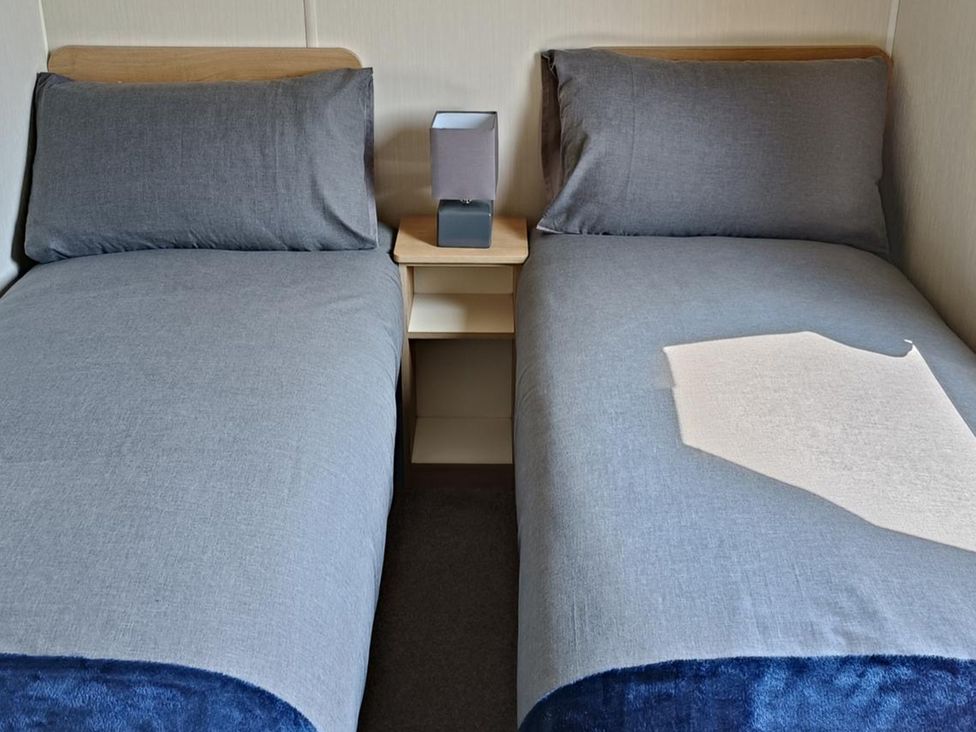 A bedroom with two beds and a lamp at Golden Sands 3-Bed Caravan, Parking and Pet Friendly in Towyn