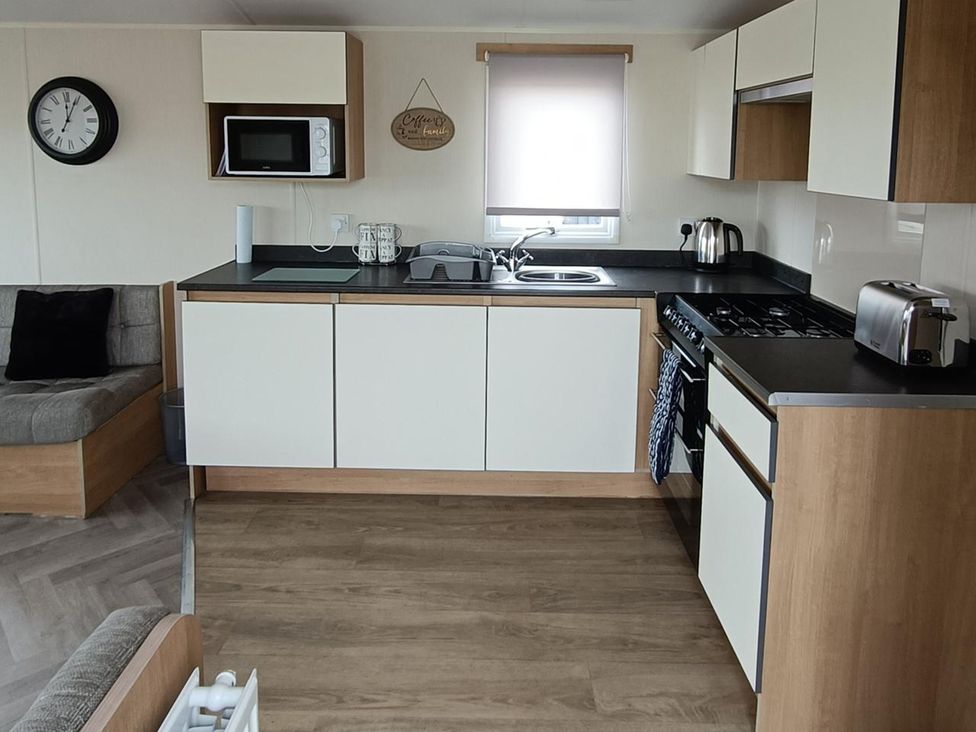 A kitchen with appliances and seating at Golden Sands 3-Bed Caravan, Parking and Pet Friendly in Towyn