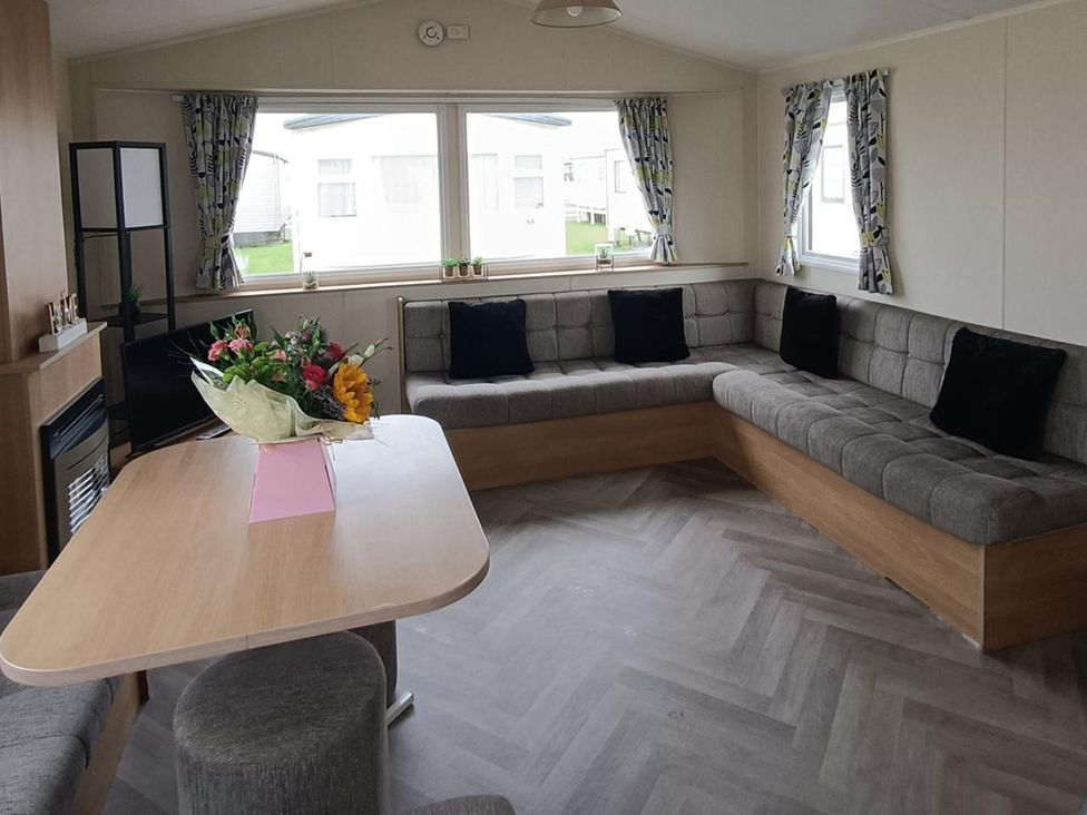 A living room with a corner sofa and a table at Golden Sands 3-Bed Caravan, Parking and Pet Friendly in Towyn