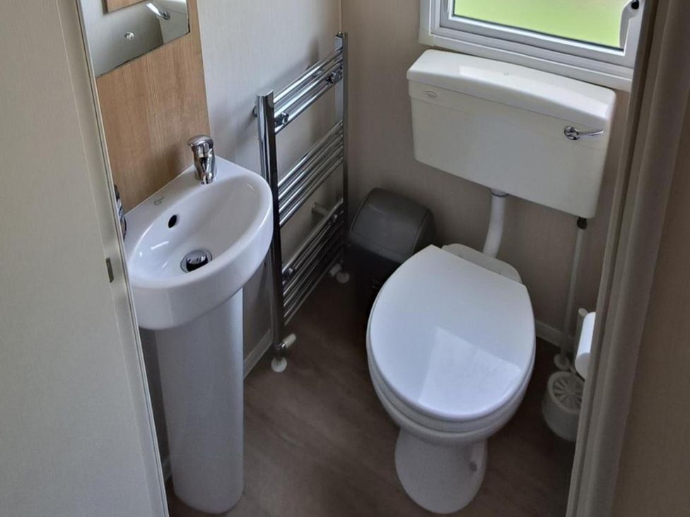A bathroom with a sink, toilet, and towel rail at Golden Sands 3-Bed Caravan, Parking and Pet Friendly, Towyn