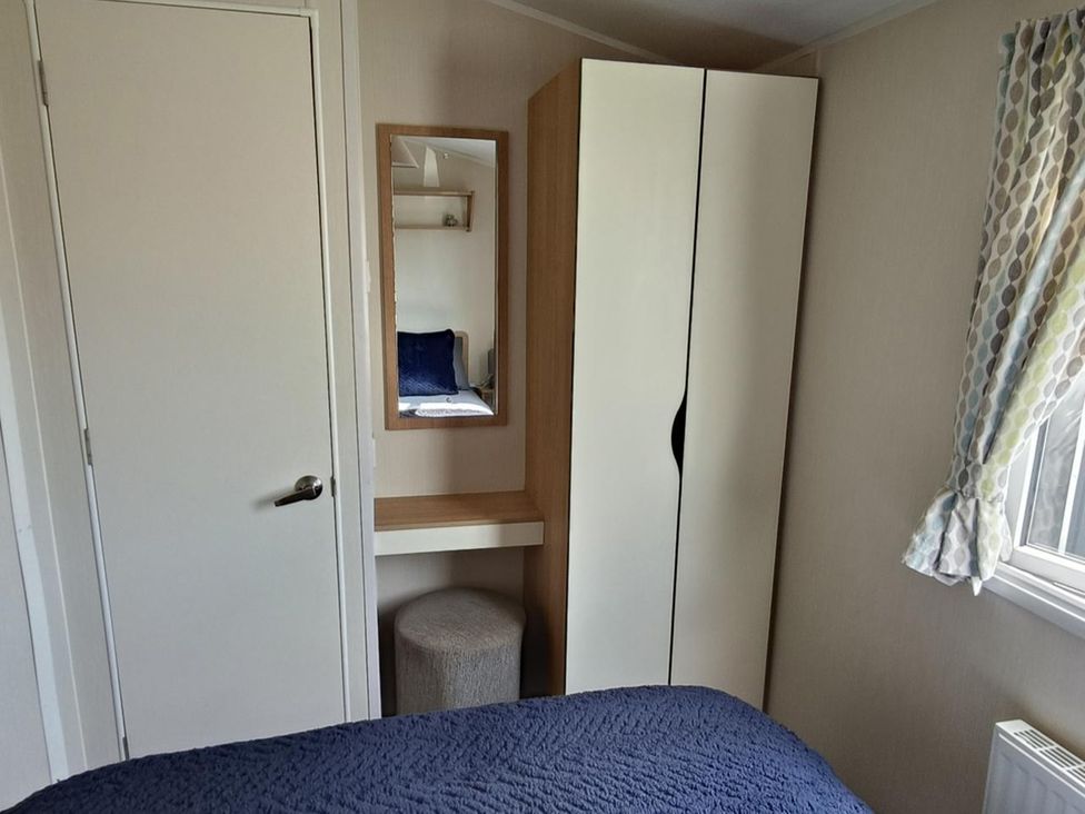 A bedroom with a wardrobe and a mirror at Golden Sands 3-Bed Caravan, Parking and Pet Friendly, Towyn