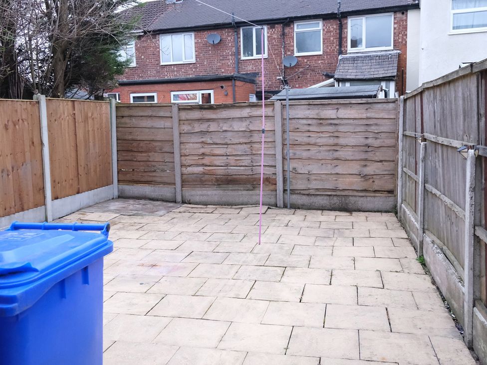 A garden with a blue bin and wooden fencing at 3 Bedroom, Modern House in Manchester