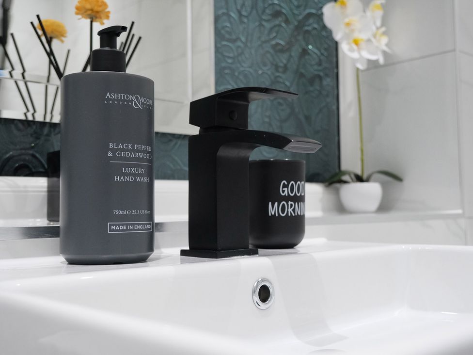 A bathroom with hand wash dispenser and mug at 3 Bedroom, Modern House in Manchester