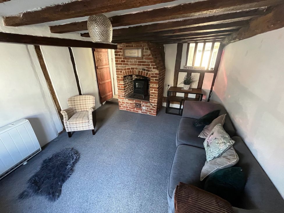 A living room with a fireplace and seating at Historic Cottage on the Suffolk border, Harleston Norfolk