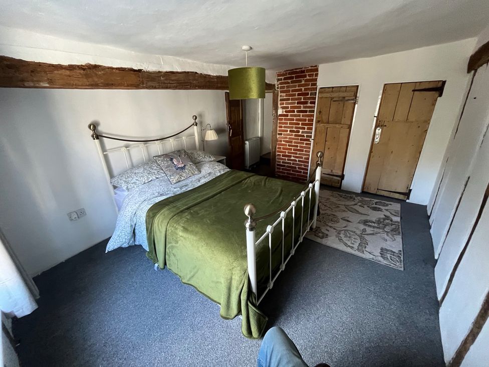 A bedroom with a bed and wooden doors at Historic Cottage on the Suffolk border, Harleston Norfolk