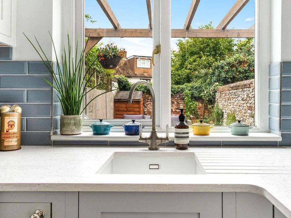 A kitchen with a sink and faucet looking out to a garden at Little Braybrooke Cottage- Saffron Walden