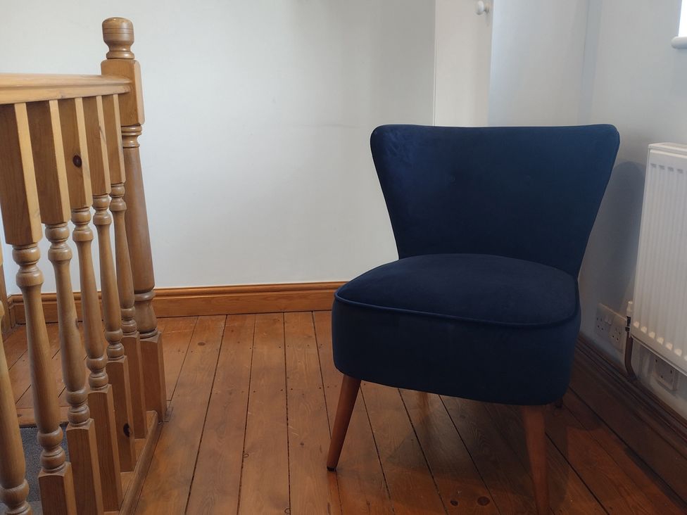 A chair next to a wooden railing at Little Braybrooke Cottage- Saffron Walden
