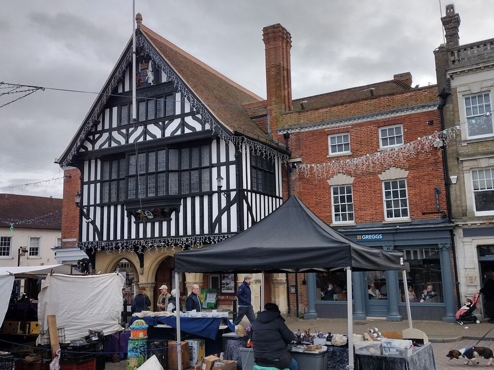 A market scene with a historic building and people at Little Braybrooke Cottage- Saffron Walden
