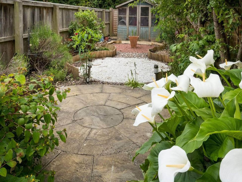 A garden with a shed, plants, and a circular stone pathway at Impeccable 3 bed 2 bath Central Cowes Cottage, Cowes