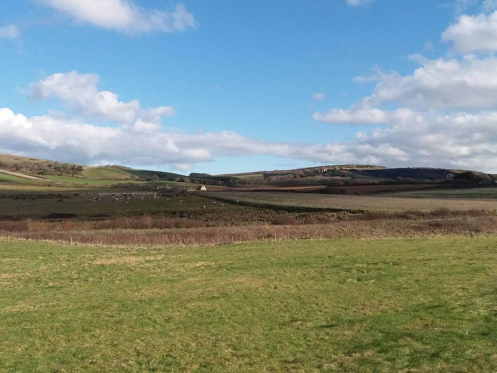 A view of rolling hills and fields with a farmhouse at Impeccable 3 bed 2 bath Central Cowes Cottage in Cowes