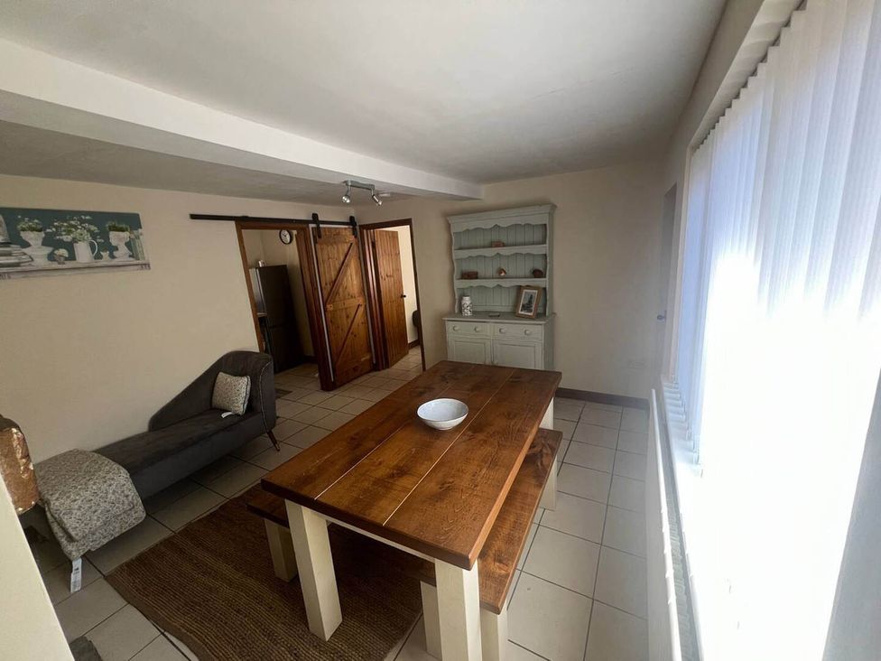 A dining room with a wooden table and a shelf at Blyton 2-Bed Cottage, Parking, 30m to Lincoln, Gainsborough