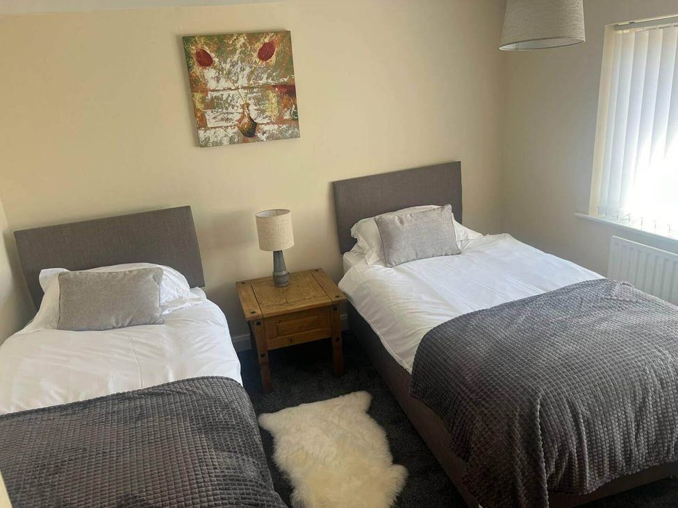 A bedroom with two single beds and a bedside table at Blyton 2-Bed Cottage, Parking, 30m to Lincoln in Gainsborough