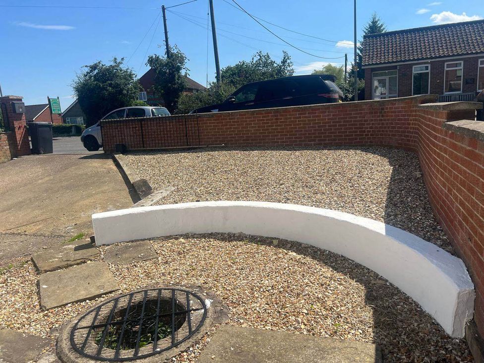 A driveway with gravel and a curved wall at Blyton 2-Bed Cottage, Parking, 30m to Lincoln in Gainsborough