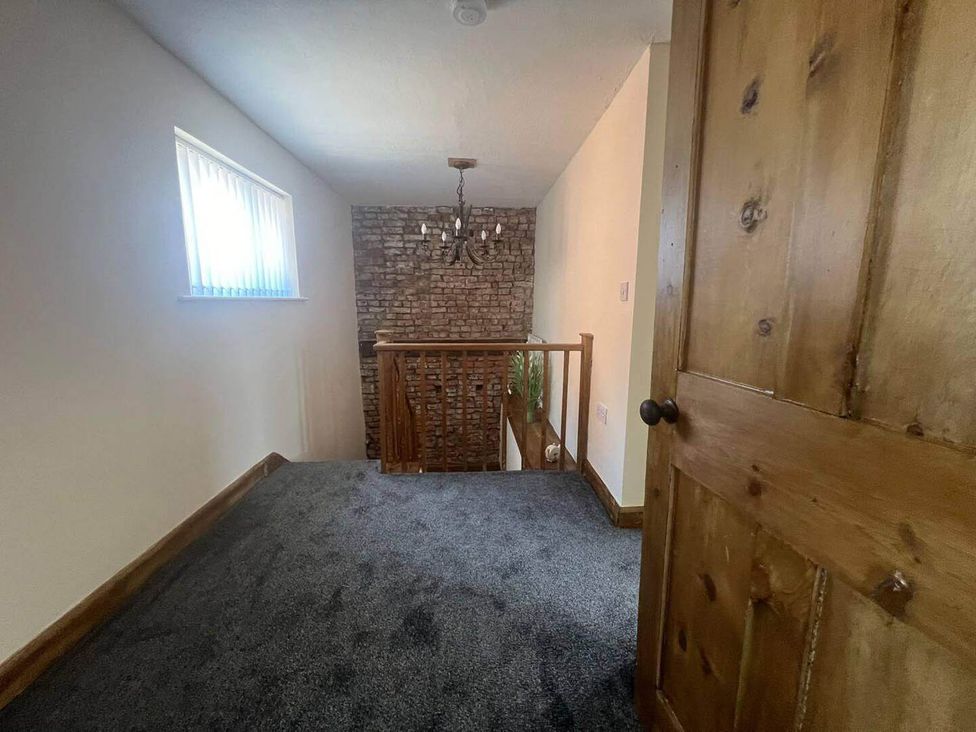 A hallway with a wooden door and a chandelier light at Blyton 2-Bed Cottage, Parking, 30m to Lincoln in Gainsborough