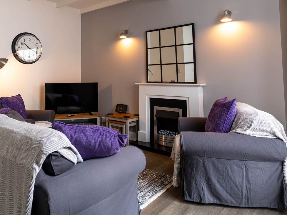 A living room with a clock and television at The Old Paint Shop Apartment - Centrally Situated Anstruther