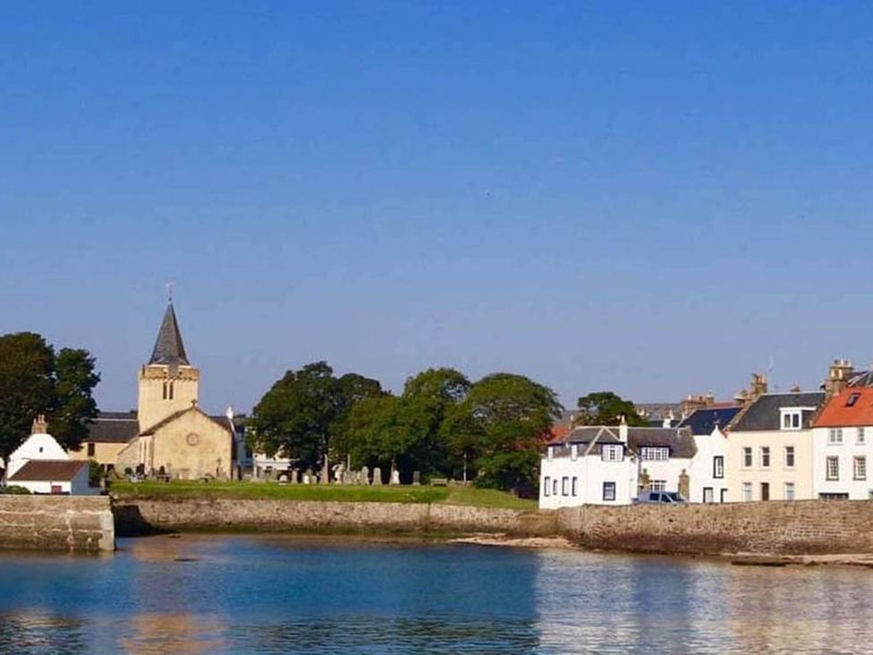 A view of a church and houses along a waterfront at The Old Paint Shop Apartment - Centrally Situated Anstruther