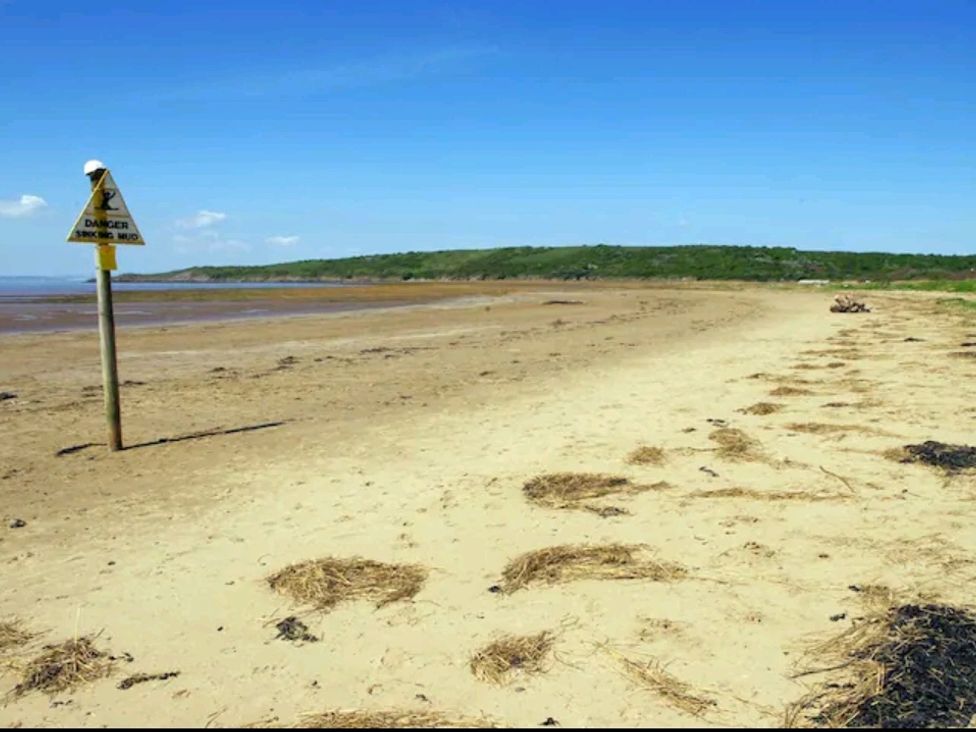 A beach with a warning sign about mud near Family Friendly Coach House - Parking - Sleeps 4 Ebdon