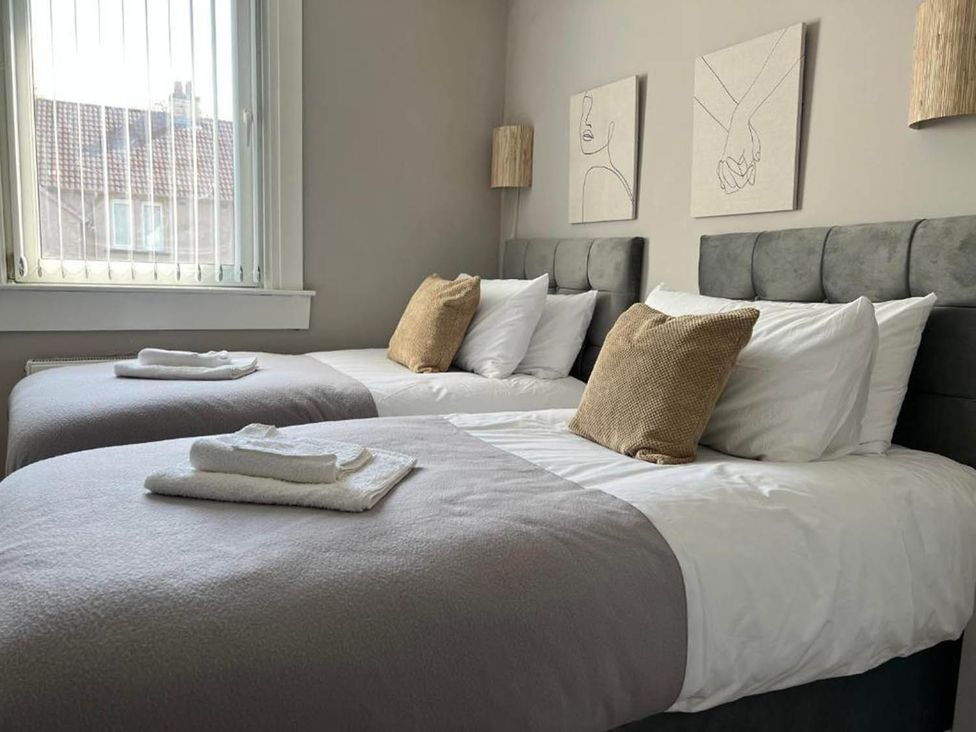 A bedroom with two beds and pictures on the wall at 3 Bedroom Flat, sleeping 6 with free parking, Kirkcaldy