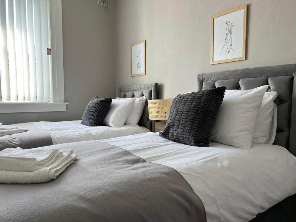 A bedroom with two beds and wall art at 3 Bedroom Flat, sleeping 6 with free parking, Kirkcaldy