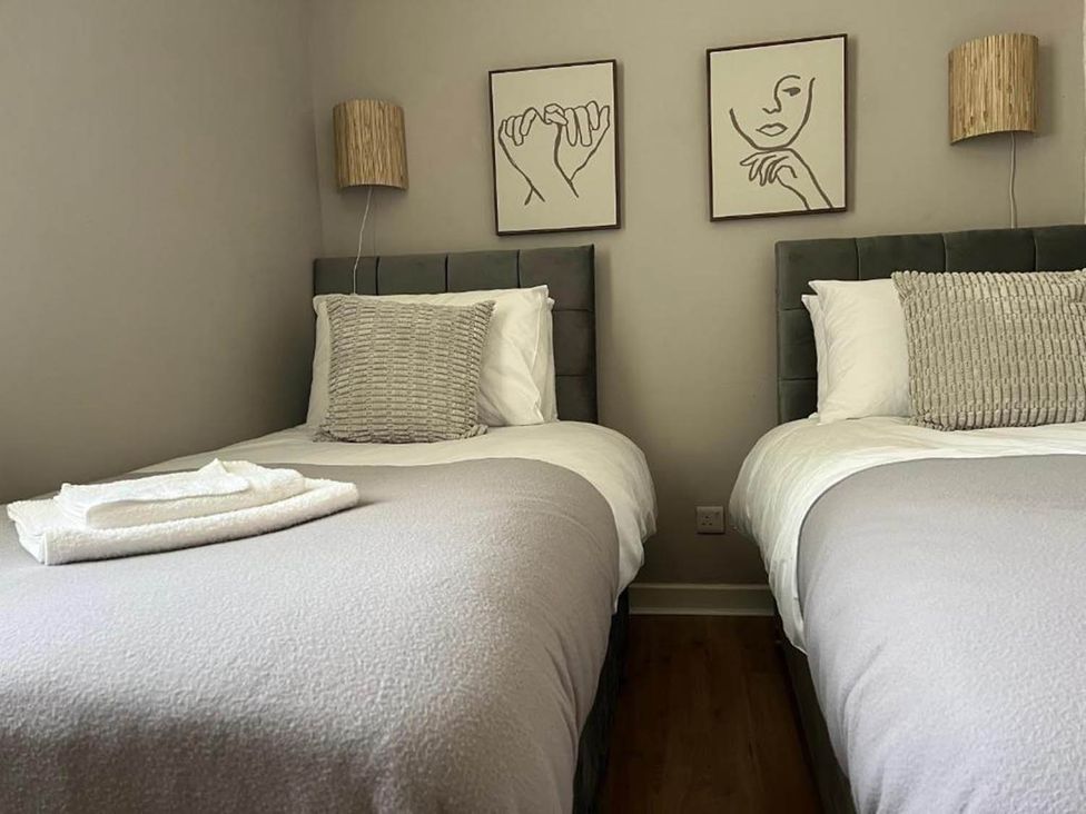 A bedroom with two beds and wall art at 3 Bedroom Flat, sleeping 6 with free parking, Kirkcaldy
