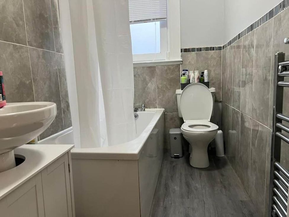 A bathroom with a sink, bath tub, toilet, and towel radiator at 3 Bedroom Flat, sleeping 6 with free parking Kirkcaldy