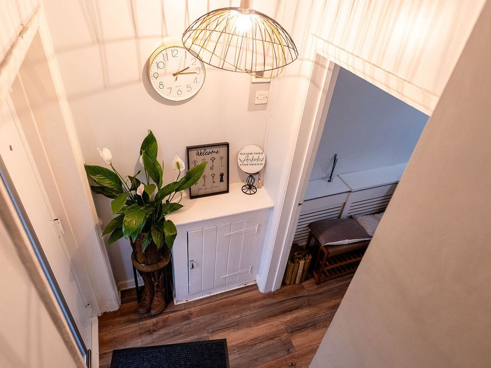 A hallway with a clock and a plant at 3 Bedroom, sleeping 5 with Wifi Wythenshawe near Manchester