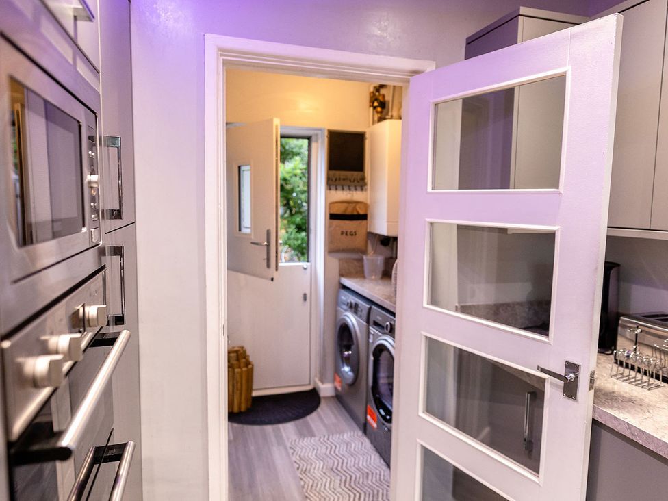 A kitchen with appliances and a door leading outside at 3 Bedroom, sleeping 5 with Wifi Wythenshawe near Manchester