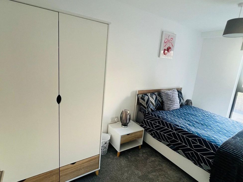 A bedroom with a bed and wardrobe at Apartment near Old Trafford, Sleeping 3 with Garden and Parking, Manchester