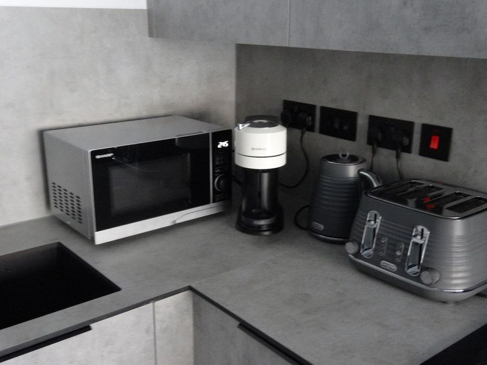 A kitchen with a microwave, coffee maker, kettle, and toaster at Apartment near Old Trafford, Sleeping 3 with Garden and Parking, Manchester
