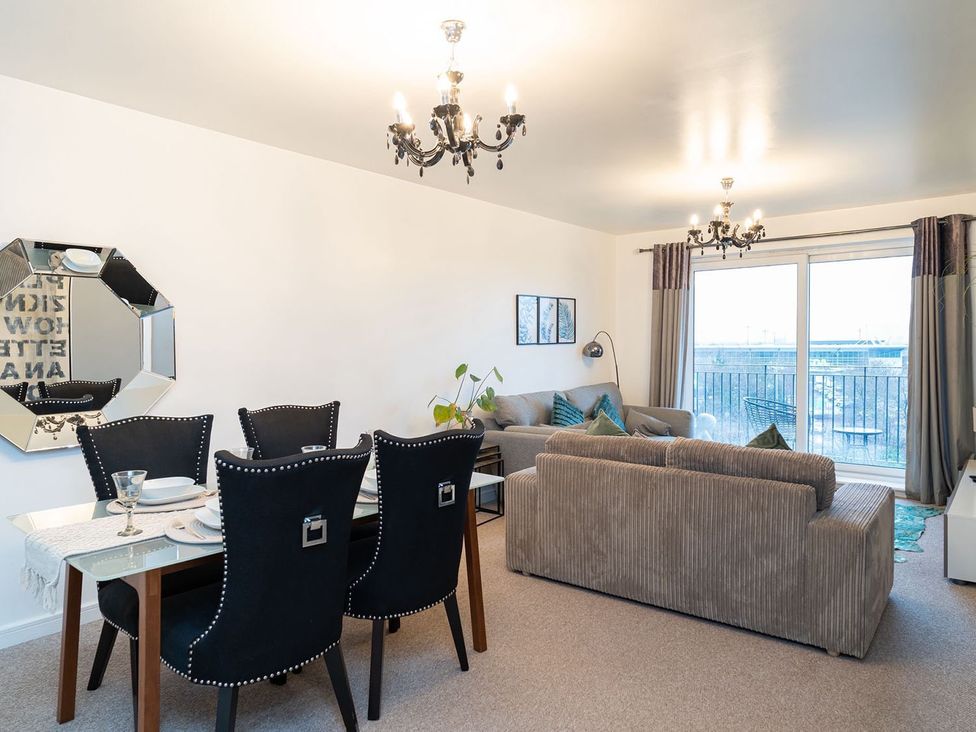 A living room with a dining area and balcony at Apartment, Sleeps 6 with Stadium View, Manchester