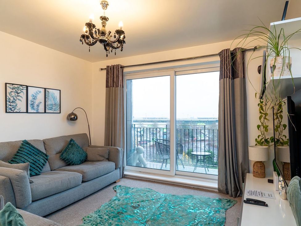 A living room with a sofa and balcony access at Apartment, Sleeps 6 with Stadium View in Manchester