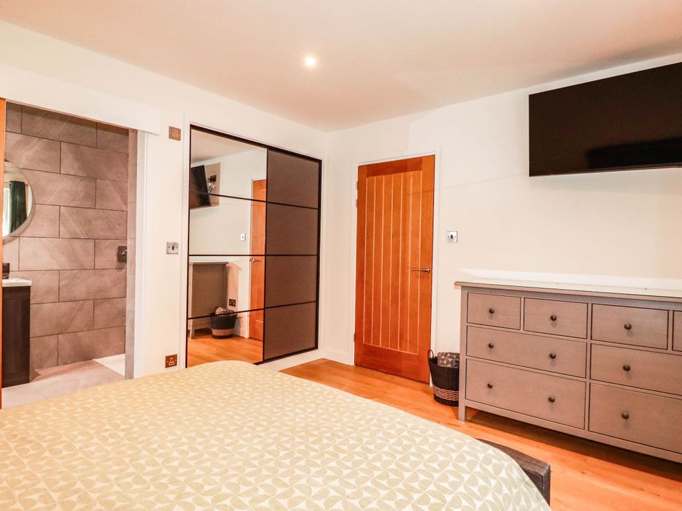 A bedroom with a bed, dresser, and mirror at Rule retreat in Penzance