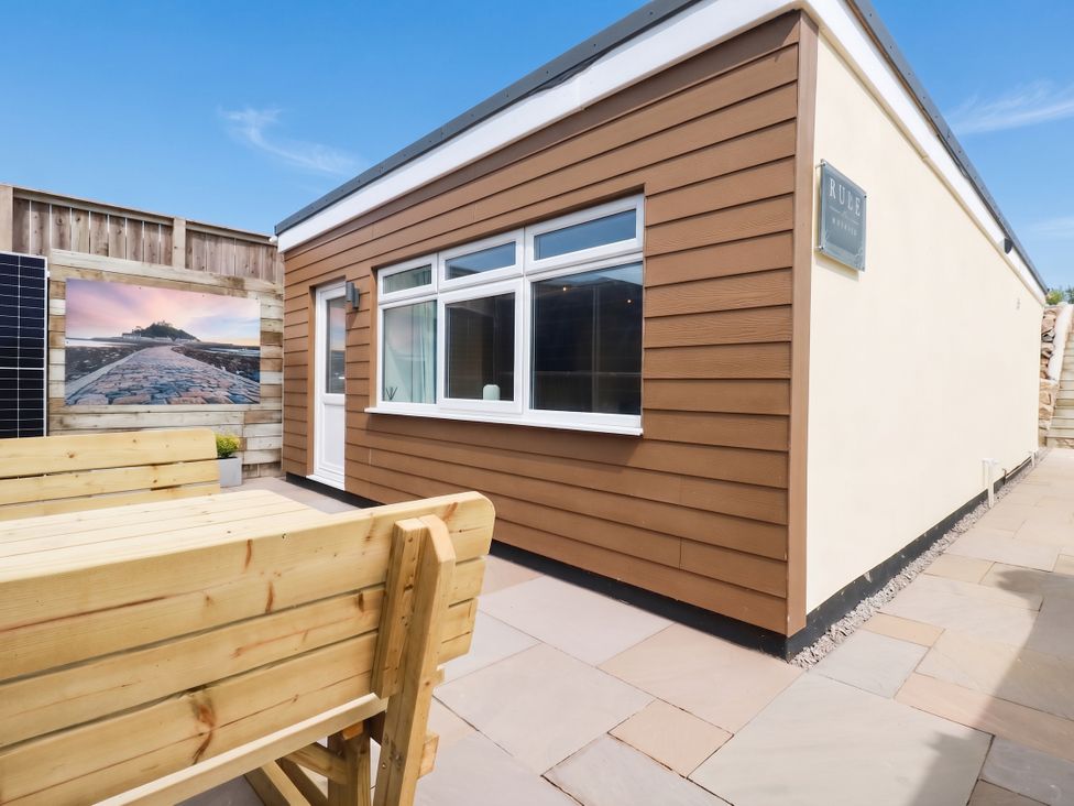An outdoor area with a wooden bench and a sign at Rule retreat in Penzance