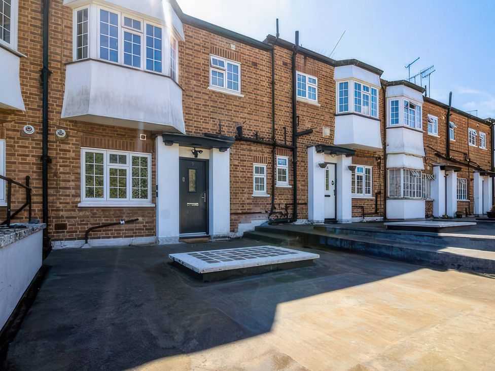 An outdoor view of townhouses with steps and a patio at 7 Wolsey Mansions Northwood, Hertfordshire