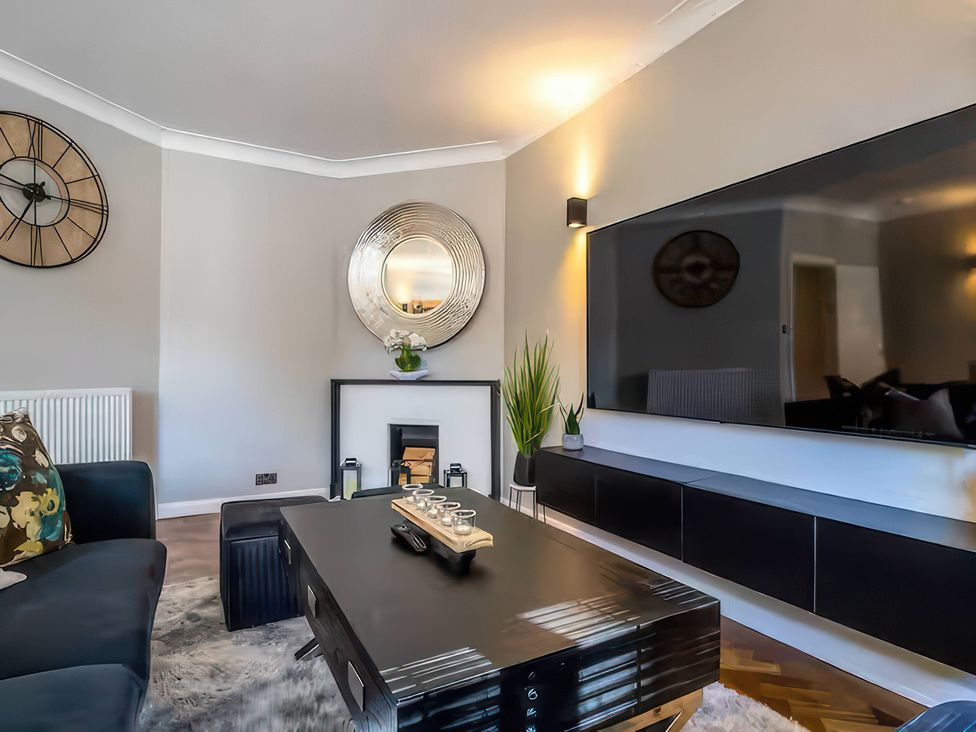 A living room with a coffee table and television at 7 Wolsey Mansions, Northwood, Hertfordshire