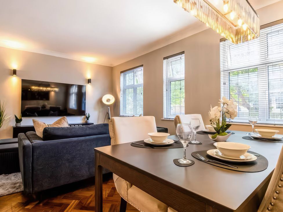 A dining room with a table set for dinner and a sofa at 7 Wolsey Mansions, Northwood, Hertfordshire