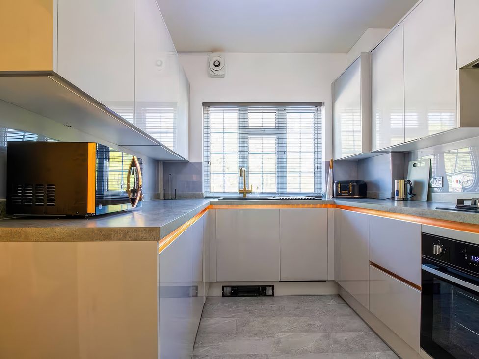 A kitchen with a sink, microwave, and a toaster at 7 Wolsey Mansions in Northwood, Hertfordshire