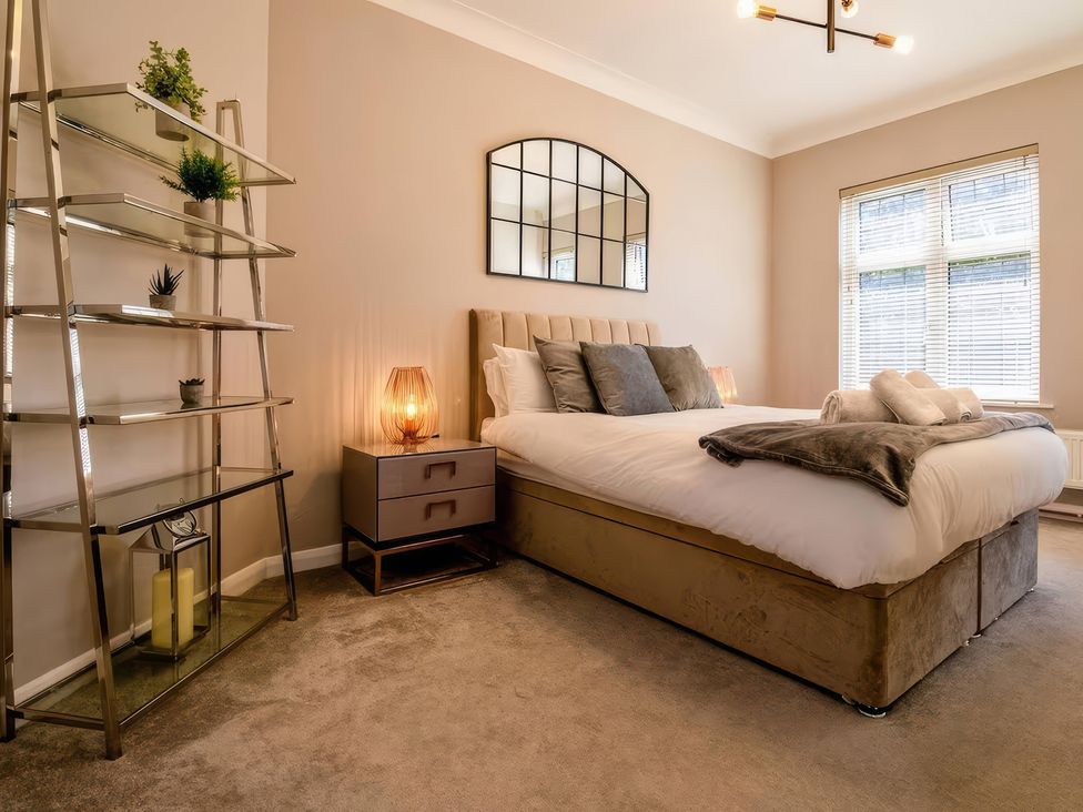 A bedroom with a bed and a shelf at 7 Wolsey Mansions in Northwood, Hertfordshire