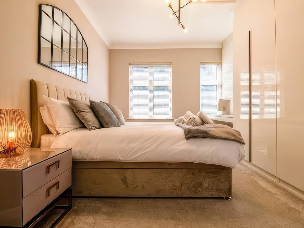 A bedroom with a bed and lamps at 7 Wolsey Mansions in Northwood, Hertfordshire