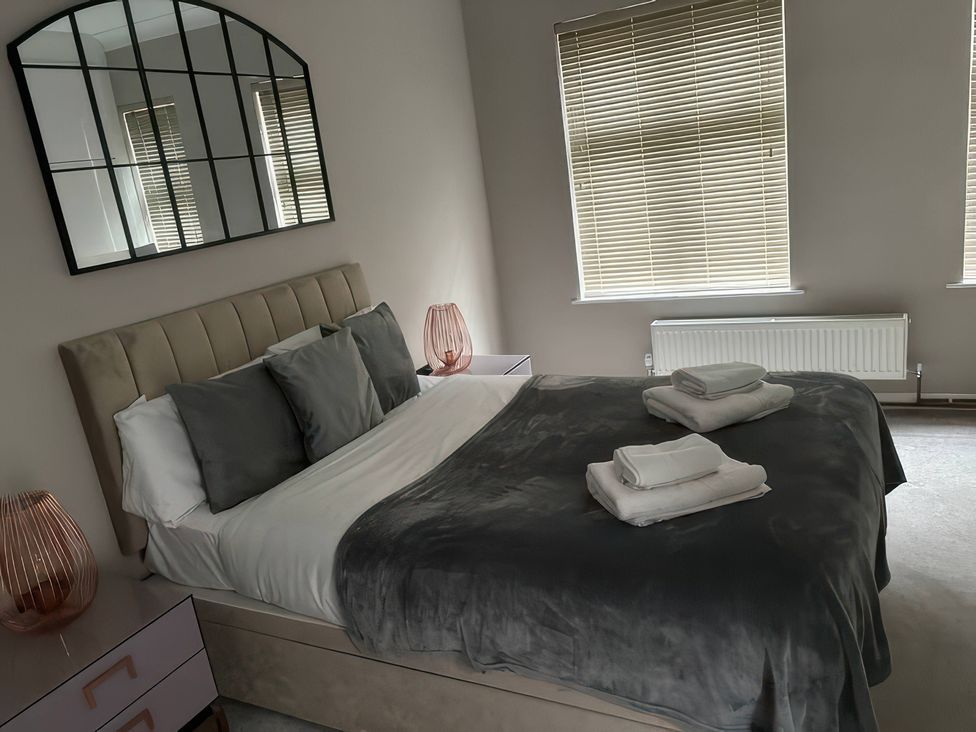 A bedroom with a bed made and a large mirror at 7 Wolsey Mansions in Northwood, Hertfordshire