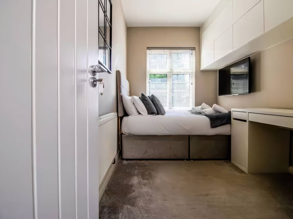 A bedroom with a bed and desk at 7 Wolsey Mansions in Northwood, Hertfordshire