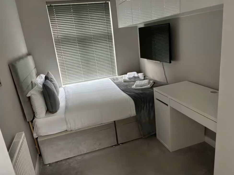 A bedroom with a bed and desk at 7 Wolsey Mansions, Northwood, Hertfordshire