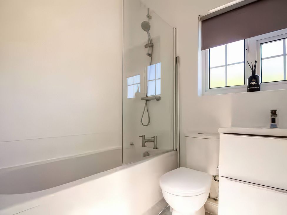 A bathroom with a shower over a bathtub and a toilet at 7 Wolsey Mansions in Northwood, Hertfordshire